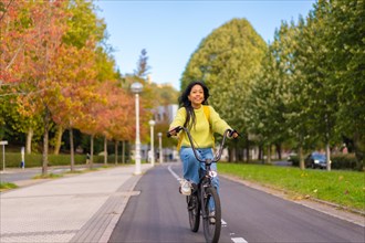 Young Asian female student riding a bicycle on her way to university along the bike lane