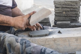 Worker manually forming a clay tile in potter factory in Fez