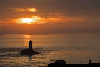 The lighthouse La Vieille in the strait Raz de Sein silhouetted against sunset at the Pointe du Raz