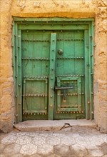 Old green door in the abandoned ghost town of Al Hamra
