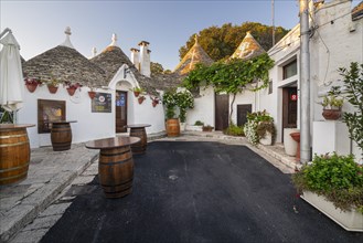 Wine barrels in front of trulli with flowers