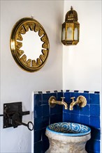 Traditional wash basin and golden mirror and lamp in the corner of the riad's bedroom