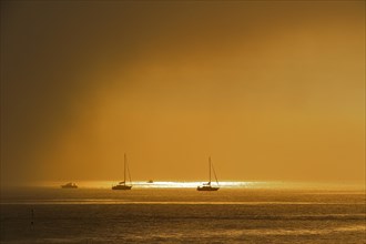 Rain cloud passing over sailing boats at sunset at Saint-Denis-d'Oleron on the island Ile d'Oleron
