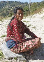 Nepalese woman with nose ring and forehead tika sitting on the ground