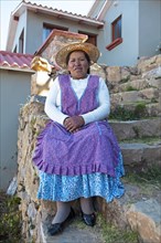 Bolivian woman in typical Bolivian clothes on the stairs in front of her house
