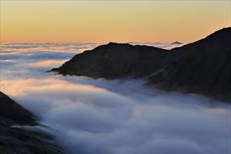 View over mountains covered in mist at sunrise seen from the Col du Tourmalet
