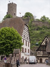 Old half-timbered house in the centre of the old town and Kaysersberg Castle tower on the hillside