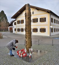 A woman lights a candle in memory of Pope Benedict XVI in front of the Benedict Column and the birthplace of Pope Benedict XVI in Maktl a. Inn