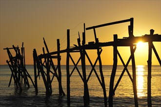 Remains of wooden walkway of traditional carrelet fishing hut on the beach at sunset