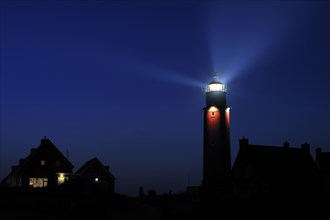 Houses and light beams from lantern of the Cocksdorp lighthouse Eierland at night