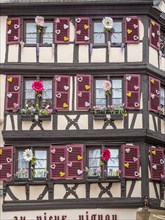 Windows of a half-timbered house decorated with flowers and hearts in the centre of the old town