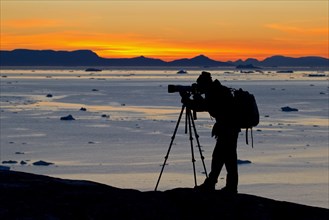 Tourist at sunset taking pictures of the Kangia Icefjord