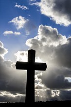Cross silhouetted against cloudy sky