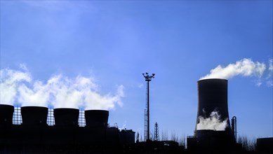 Industrial estate showing cooling tower and chimneys silhouetted against blue sky at the BASF chemical production site in the port of Antwerp