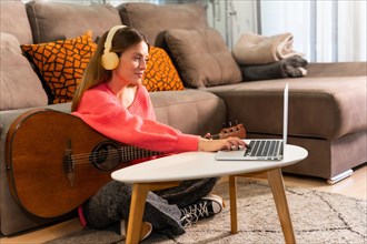 Woman learning to play the guitar at home with online classes on the computer
