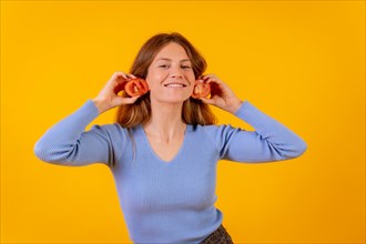 Vegan woman smiling with earrings tomato slices on a yellow background