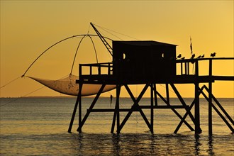 Traditional carrelet fishing hut with lift net on the beach at sunset