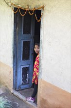 Nepalese girl looking out of a door frame