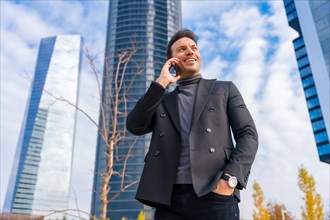 Corporate portrait of middle-aged businessman talking on the phone next to skyscraper office