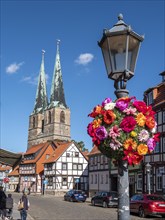 Flower-decked streetlamp and in the background half-timbered house and St. Nicholas Church in the centre of the old town