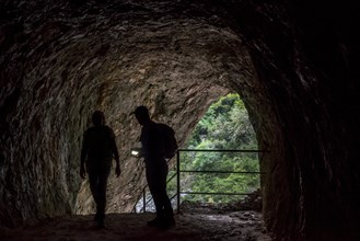 Two walkers with torch entering tunnel on the Sentier Martel path in the Gorges du Verdon