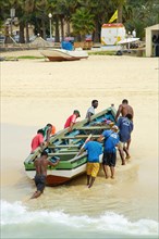 Nine 9 local fishermen pull wooden fishing boat from sea to beach