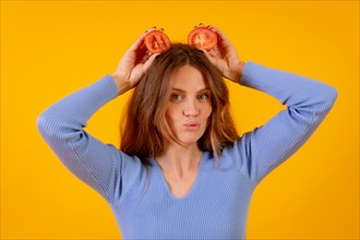Vegan woman with tomato slices on her head on a yellow background