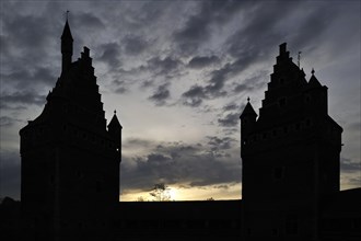Silhouetted step-roofed towers of the medieval Beersel Castle at sunset