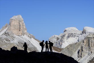 Four mountain climbers silhouetted against Torre dei Scarperi