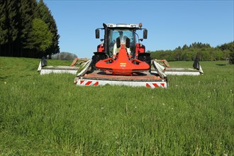 Tractor with three mowers cuts high grass