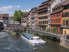 Lock bridge and excursion boat on the Ill and colourful half-timbered houses