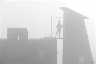 Medieval siege weapons and wooden attack tower silhouetted in the mist at the mediaeval fortified village Larressingle in the Pyrenees