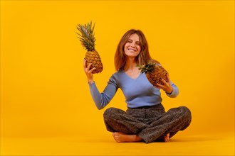 Vegetarian woman smiling with a cut pineapple sitting down