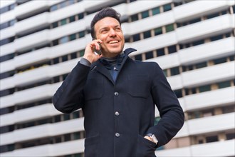 Middle-aged Caucasian businessman talking on the phone in the city smiling