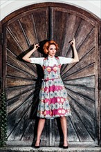 Portrait of a woman in dirndl in front of a wooden wall
