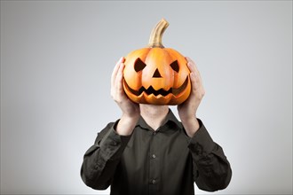 Man holding a clay pumpkin in front of his head | MR:yes ph_halloween_mr