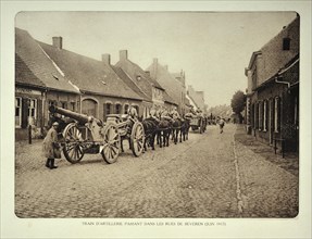 Artillery soldiers transporting cannons by horse through the village Beveren in Flanders during the First World War