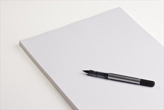 Blank pad of white paper with a pen on a white background