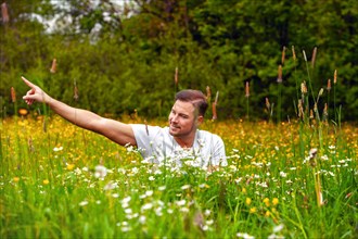 Man sitting in a field of flowers with arm outstretched