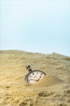 Pocket watch buried in a sandy beach