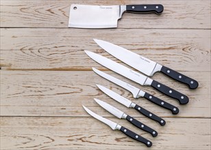 An assortment of various kitchen knives on a wooden background