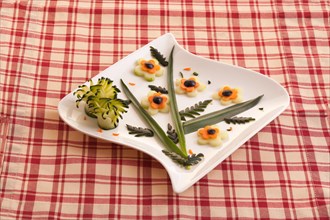 Appetizer plate with carved raw vegetables of cucumber