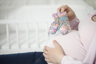 Pregnant woman with knitted socks on her baby bump