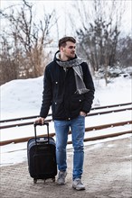Young man in winter with suitcase