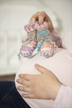 Pregnant woman with knitted socks on baby belly | MR:yes NH_pregnant_belly_mr
