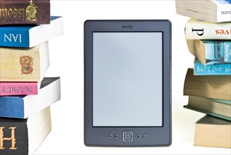 Kindle e reader with a large pile of books