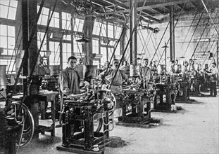 Early 20th century black and white archival photo showing workers and machines for casting types for typesetters at foundry floor of type foundry