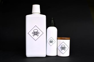 Different shaped white containers with poison labels on black background