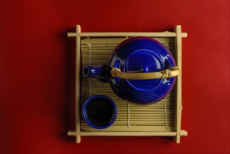 Oriental tea pot and bowl sitting on a bamboo tray