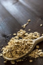 Wooden spoon with rolled porridge oats on a wooden background
